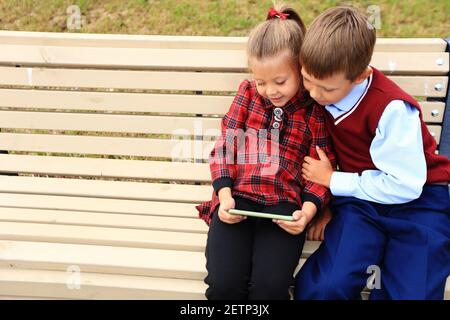 Kinder mit Aktentaschen über den Schultern auf dem Hintergrund der Schule. Stockfoto