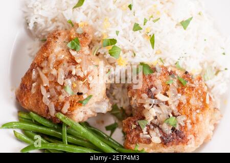 Knusprig gebratene Hähnchenschenkel mit Gemüse über Reis in einem Zitronensauce Stockfoto