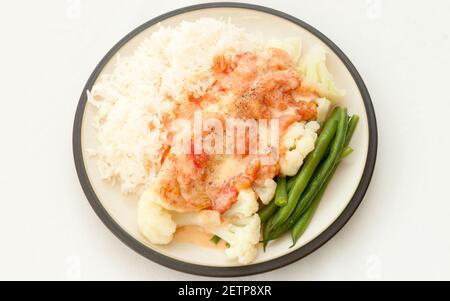 Ein Herz gesunde Mahlzeit pochierte Tilapia Fischfilets mit Erbstück Tomaten und Bohnen über weißem Reis Stockfoto