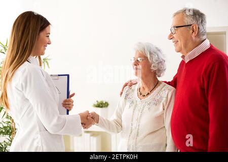 Lächelndes und glückliches Senioren-Paar, das einen Arzt in der Klinik besucht Stockfoto