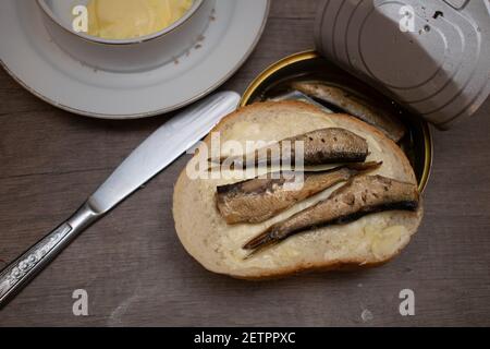 Sprotte auf Brot mit Blechdose und schmutziger Tischplatte. Stockfoto