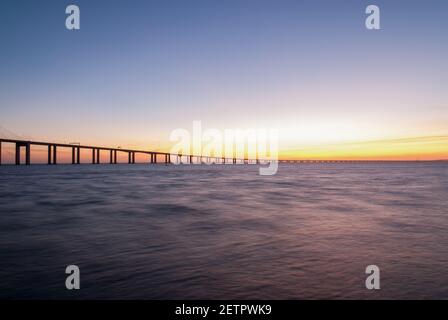 Eine Landschaft der Vasco da Gama Brücke über den Tejo Fluss mit langer Belichtung während des Sonnenuntergangs in Lissabon, Portugal Stockfoto