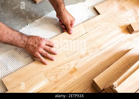 Montage von gemusterter Holzoberfläche auf einem stabilen Gemisch Unterboden Leim Stockfoto