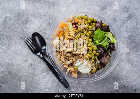 Gesunde Schüssel zum Mittagessen. Hühnchen, Nudeln Fusilli, mischen Sie Gemüse, grüne Erbsen und Sonnenblumenkerne in Plastic Schüssel. Köstliches ausgewogenes Food-Konzept. Draufsicht, Cop Stockfoto