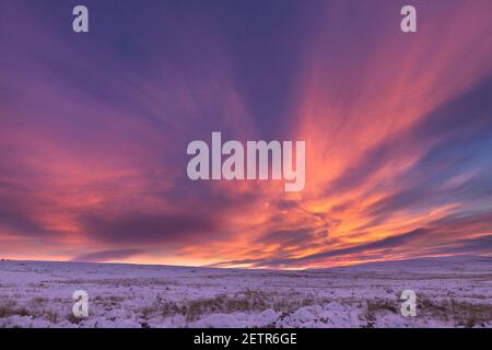 Ein spektakulär feuriger Winteruntergang über Cold Fell, Geltsdale und den angrenzenden Hügeln, von Plenmeller Common, Northumberland, Großbritannien aus gesehen Stockfoto