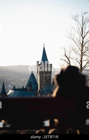Nahaufnahme Aufnahme bei Sonnenuntergang auf Schloss Wernigerode in Deutschland. Junge Frau sitzt auf der Bank und schaut zum castl Stockfoto