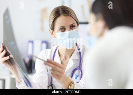 Arzt in Schutzmaske mit Röntgenaufnahme des Patienten Stockfoto