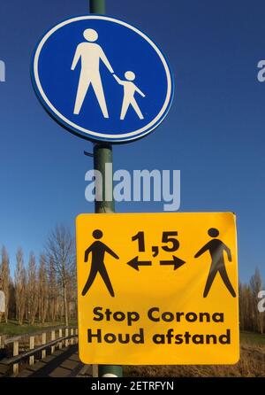 Verkehrsschild für einen Fußpfad, mit einem Corona-Warnschild darunter für die Einhaltung der Distanz in Niederländisch Stockfoto