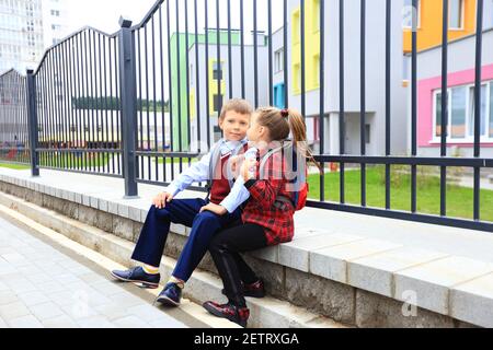 Kinder mit Aktentaschen über den Schultern auf dem Hintergrund der Schule. Stockfoto