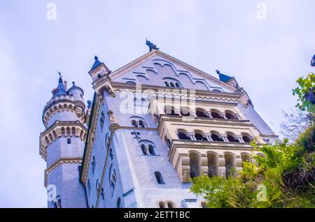 neuschwanstein, berühmtes Schloss der Märchen, Prinzessinnen und Liebenden, sticht vor dem blauen Himmel und den Wäldern vor der Kulisse der Seen hervor Stockfoto