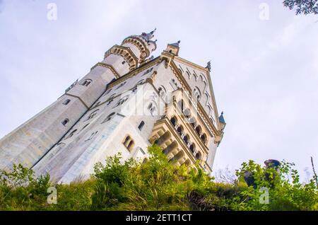 neuschwanstein, berühmtes Schloss der Märchen, Prinzessinnen und Liebenden, sticht vor dem blauen Himmel und den Wäldern vor der Kulisse der Seen hervor Stockfoto