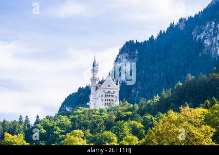 neuschwanstein, berühmtes Schloss der Märchen, Prinzessinnen und Liebenden, sticht vor dem blauen Himmel und den Wäldern vor der Kulisse der Seen hervor Stockfoto