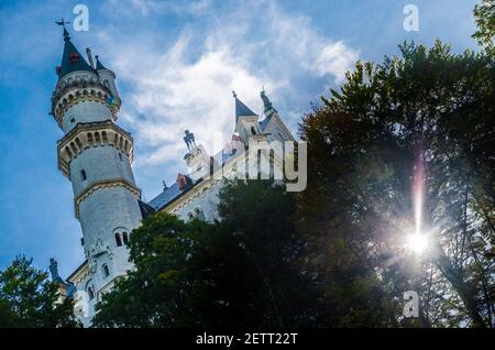 neuschwanstein, berühmtes Schloss der Märchen, Prinzessinnen und Liebenden, sticht vor dem blauen Himmel und den Wäldern vor der Kulisse der Seen hervor Stockfoto