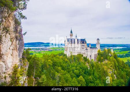 neuschwanstein, berühmtes Schloss der Märchen, Prinzessinnen und Liebenden, sticht vor dem blauen Himmel und den Wäldern vor der Kulisse der Seen hervor Stockfoto