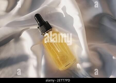 Kleine Glasflasche mit Pipette auf weißem Tuch Stockfoto