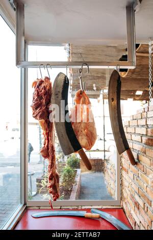 Fleisch auf dem Metzgermarkt mit Messern aufgehängt. Stockfoto