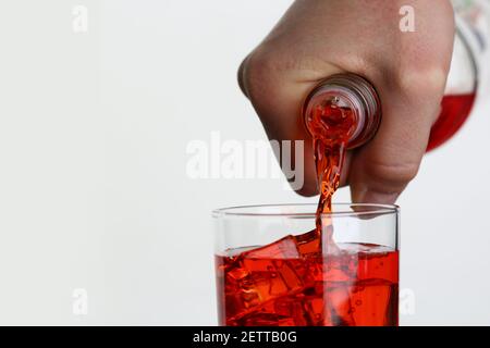 Mann gießt Orangengetränk in Glas mit Eis Nahaufnahme Stockfoto