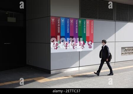 Tokio, Japan. März 2021, 01st. Ein Mann, der eine Maske trägt, als vorbeugende Maßnahme gegen die Verbreitung von covid-19, geht an einem Werbebanner der Olympischen Spiele 2020 in Tokio an einer Wand des Bunkyo Civic Center vorbei. Kredit: SOPA Images Limited/Alamy Live Nachrichten Stockfoto