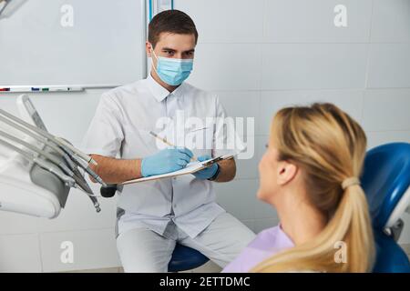 Zahnchirurg notieren die Informationen von weiblich Stockfoto