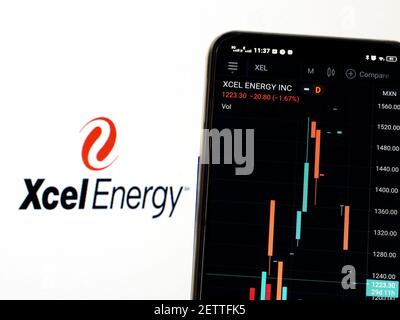 In dieser Abbildung werden die Börseninformationen von Xcel Energy Inc. Auf einem Smartphone angezeigt, während das Logo von Xcel Energy Inc. Als Hintergrund angezeigt wird Stockfoto