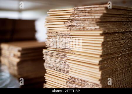 Nahaufnahme vieler aufeinander abgestimmter brauner Kartonstapel im Lagerraum der Produktionsfabrik. Stockfoto