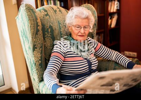 Ältere alte Frau in Panik zu Hause entspannen beim Lesen Eine Zeitung Stockfoto