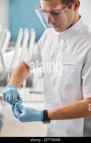 Facharzt, der die Bur in ein zahnmedizinisches Handstück legt Stockfoto