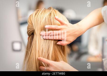 Nahaufnahme der weiblichen Friseur Styling blonde Haare von einem Junge Frau in einem Schönheitssalon Stockfoto