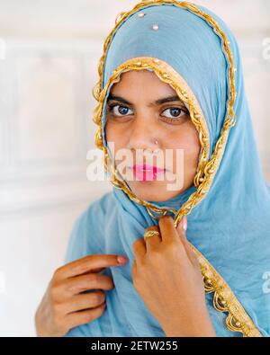 Ehrliches Porträt einer jungen Inderin mit schönen Augen und blauem Schal und rotem Lippenstift in Agra, Uttar Pradesh, Indien. Stockfoto