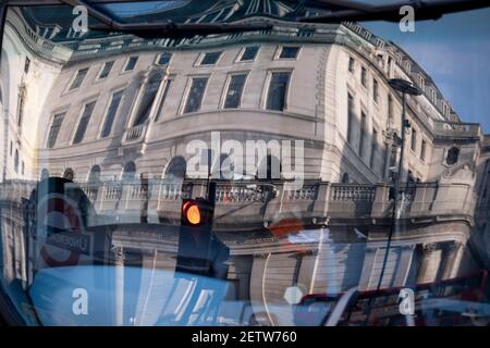 Wenige Tage bevor der Kanzler Rishi Sunak sein Budget liefert, spiegelt sich die verzerrte Architektur der Bank of England in der Windschutzscheibe eines Londoner Busses wider, der am 1st. März 2021 in London, England, durch die City of London, das Finanzviertel der Hauptstadt, fährt. Stockfoto