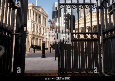 Wenige Tage bevor der Kanzler Rishi Sunak sein Budget abgibt, sieht man durch die halb geöffneten Tore eines Eingangs zur U-Bahn-Station Bank in der City of London, dem Finanzviertel der Hauptstadt, einen weiten Blick auf die Bank of England und die Statue eines berittenen Herzogs von Wellington. Am 1st. März 2021 in London, England. Stockfoto