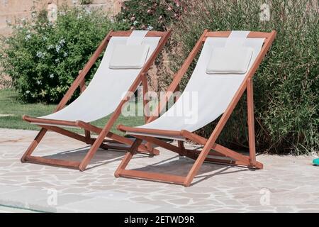 Schwimmbad mit klarem blauem Wasser und zwei Sonnenliegen am sonnigen Tag in einem Hof, schöner Urlaub für Entspannung und Freizeit, Konzept der Achtsamkeit gut bei Stockfoto