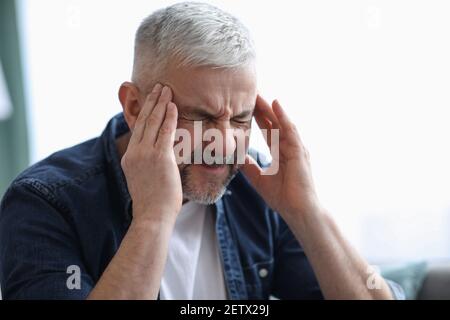 Nahaufnahme eines reifen grauhaarigen Mannes, der an Kopfschmerzen leidet Stockfoto