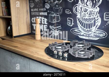 Moderne Küchenausstattung Konzept schwarz gehärtetem Glas runde Form Gas Kochfeld mit gusseisernem Grill mit drei Gasbrennern auf gebürstetem Eiche Arbeitsplatte für Stockfoto