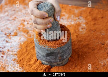 Indische Frau Handpudering indische Gewürze Red Chilly, Chili Paprika Pulver Spritz Explosion mit Steinmörtel indische Küche Kerala Indien Sri Lanka Stockfoto