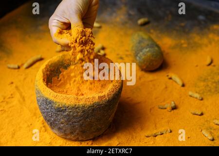 Frau Handpudering indischen Gewürzen Kurkuma Pulver Spritzer Explosion Stein Mörser Kerala Indien Sri Lanka traditionelle indische Küche Masala für Curry Stockfoto