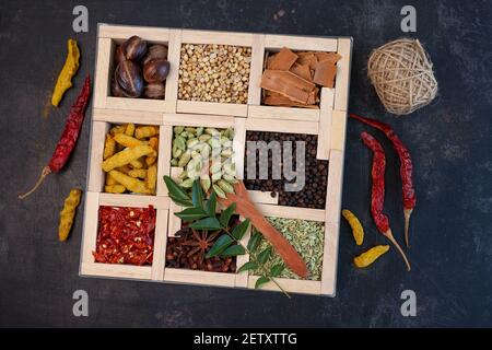 Indische Gewürze für indische Küche Masala scharf würzigen Curry ganze Gewürze Kurkuma, Kardamom, schwarzer Pfeffer in Holzlöffel Curry Blätter Paprika in indischen Stockfoto