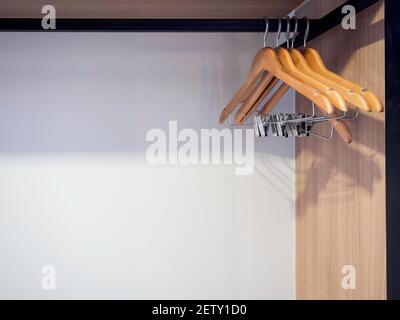 Leere Kleiderbügel aus Holz im Schrank des Hotels. Kleiderbügel aus Holz, der auf der Garderobe auf weißem Hintergrund mit Kopierfläche hängt. Stockfoto