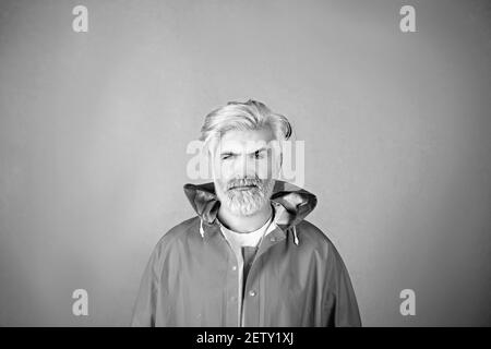 Porträt eines reifen Mannes mit gelben Haaren in einem gelben Regenmantel isoliert auf gelbem Hintergrund. Stockfoto