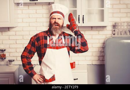 Aufgeregter Mann Koch Koch trägt Uniform zeigt Masterclass Kochen Gericht. Stockfoto