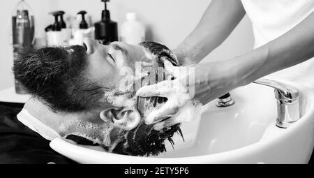 Nahaufnahme eines brutalen kaukasischen Mannes, der seine Haare im Friseursalon gewaschen hat. Friseur Waschkopf Client. Friseur bei der Arbeit. Stockfoto