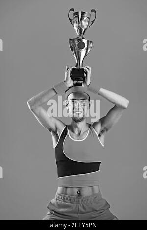 Glücklicher Sieger drückt sich den Siegerpokal auf gelbem Hintergrund zu. Stockfoto