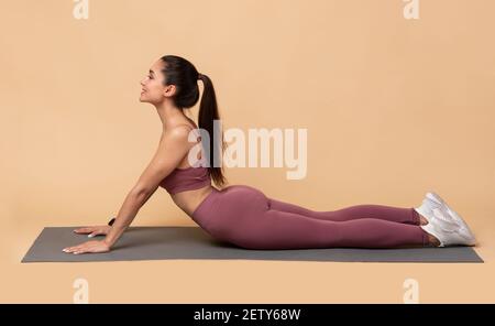Schöne Frau, die Yoga-Übungen in Kobra Pose auf Matte macht Stockfoto