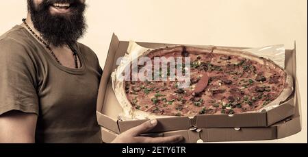 Pizza Lieferung Kurier in Uniform bietet die Pizza in Box. Stockfoto