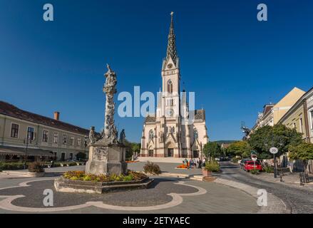 Kirche des heiligen Herzens, 1894, neugotischer Stil, Säule der Heiligen Dreifaltigkeit (Pestsäule), 1713, auf dem Fo Ter (Hauptplatz) in Koszeg, Ungarn Stockfoto