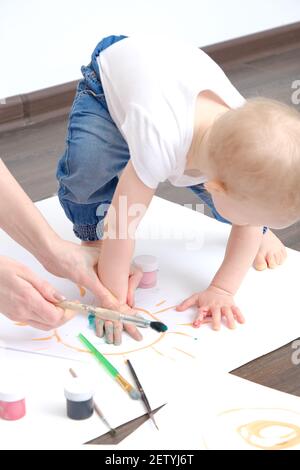 Junge Mutter und ihr Kind spielt mit Aquarellen Stockfoto