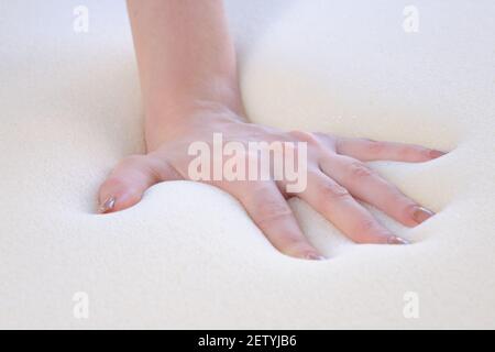 Eine Frauenhand drückt auf die Nahaufnahme von Schaumgummi-Checks Seine Weichheit Stockfoto
