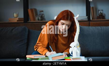 Junge Studentin hält Stift in der Nähe von Büchern und Wirbelsäulenmockup Stockfoto