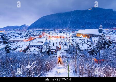 Brasov, Siebenbürgen. Winternachtslandschaft mit Innenstadt und Karpaten. Reisehintergrund in Rumänien. Stockfoto