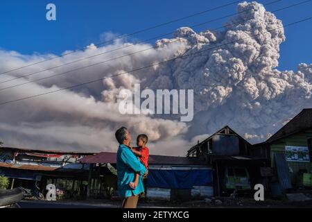 Karo, Nord-Sumatra, Indonesien. März 2021, 2nd. Die Menschen blicken auf den Berg Sinabung, der während eines Ausbruchs in Karo, Nord-Sumatra, am 2. März 2021 vulkanisches Material spuckt. Der 2.600 Meter (8.530 Fuß) große Vulkan brach am Dienstag aus, schickte Vulkangestein fünftausend Meter in den Himmel und hinterlassenAsche in nahe gelegenen Dörfern. Es gab keine Berichte über Verletzte oder Schäden. Quelle: Albert Ivan Damanik/ZUMA Wire/Alamy Live News Stockfoto